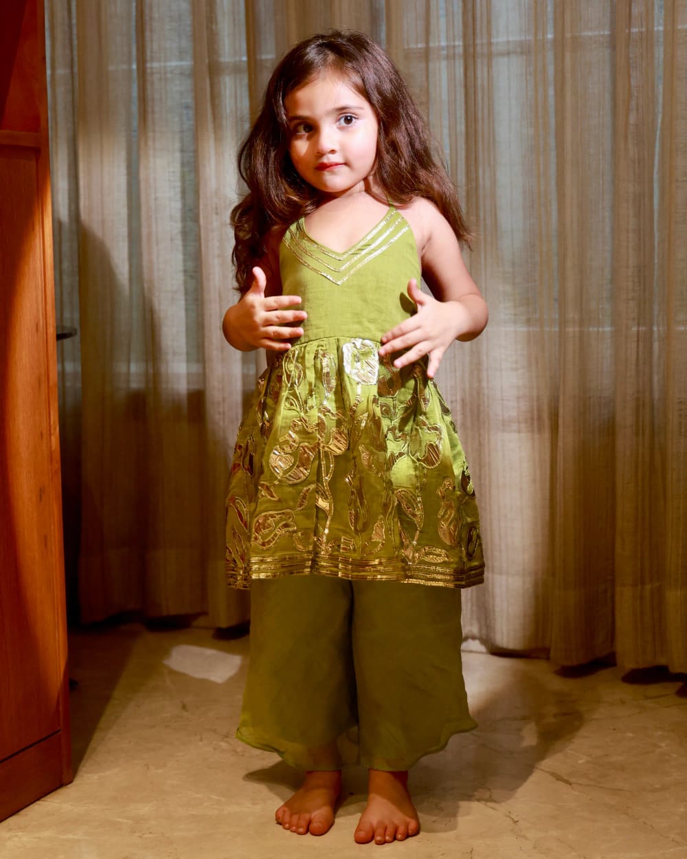 A girl in an olive kurta with a gold brocade hem, worn over matching palazzo