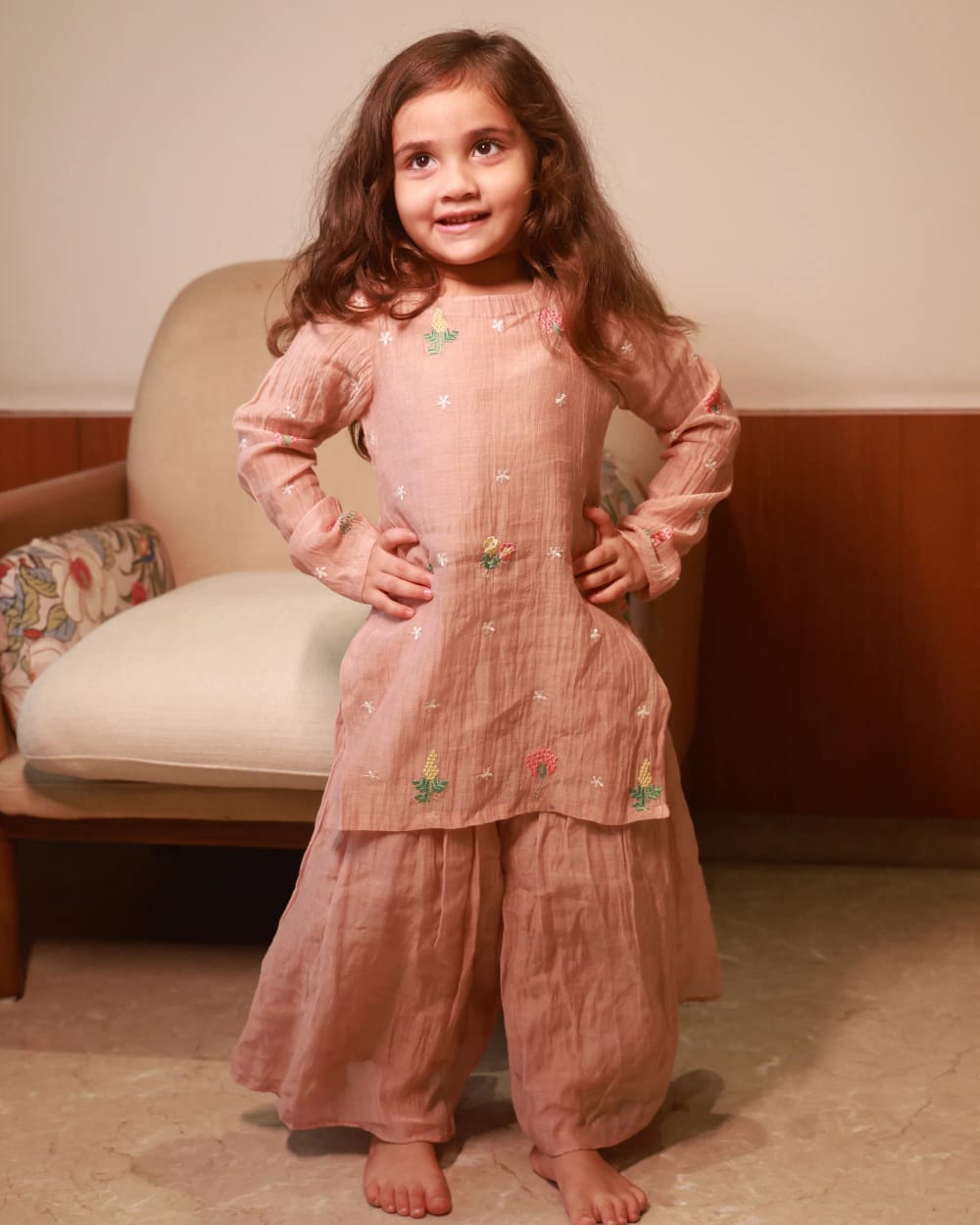 A girl in a dusty rose kurta embroidered with small flowers, over a matching sharara