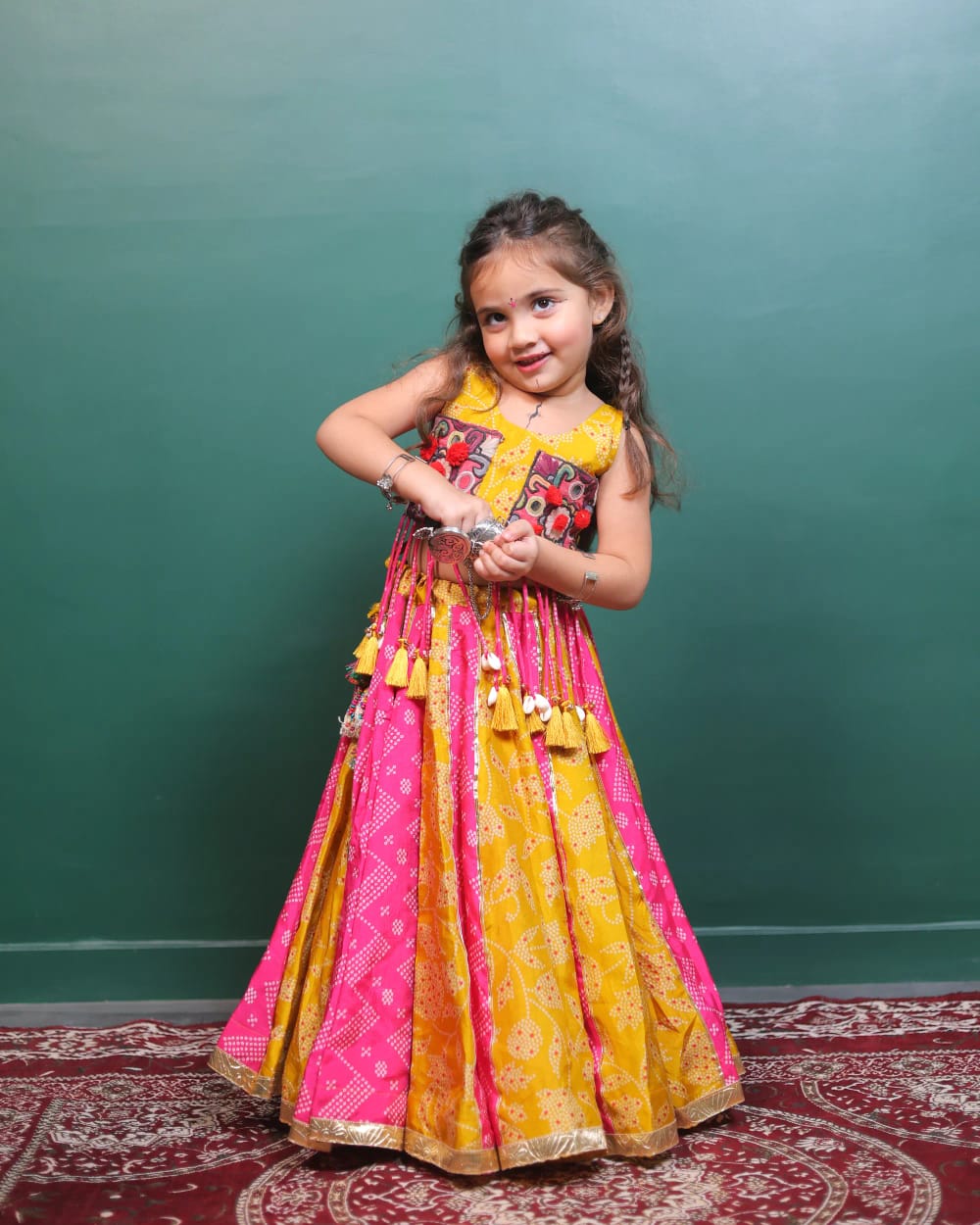 The pink and mustard bandhani ghagra at full length, its panels alternating around the skirt