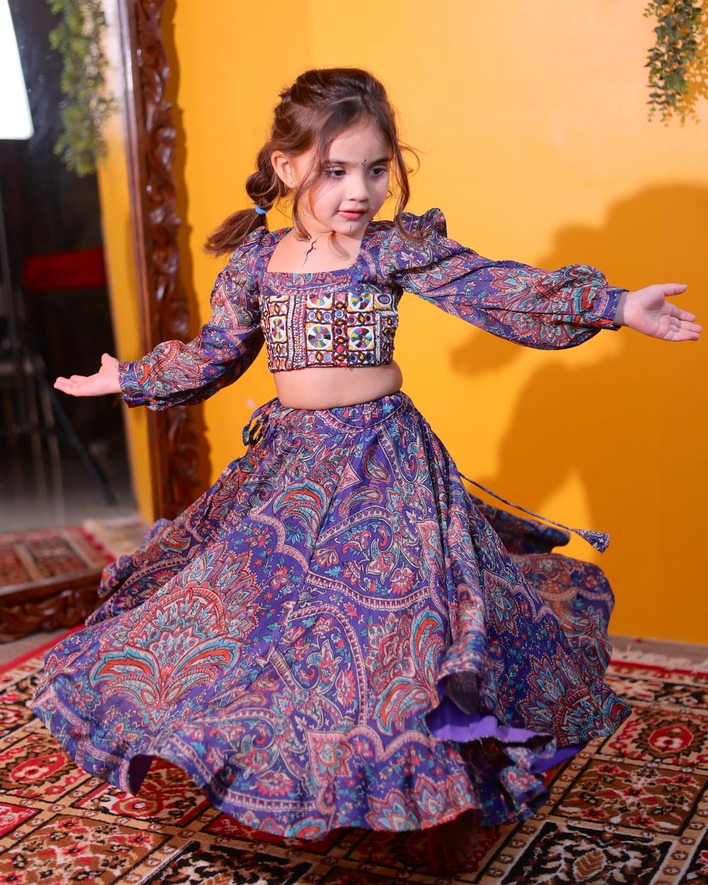 A girl mid-twirl in a violet paisley lehenga, the skirt opening around her