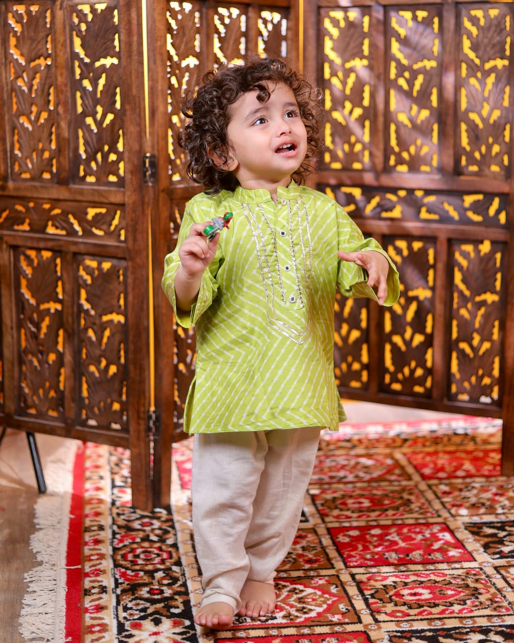 A boy in a lime leheriya kurta and cream pyjama