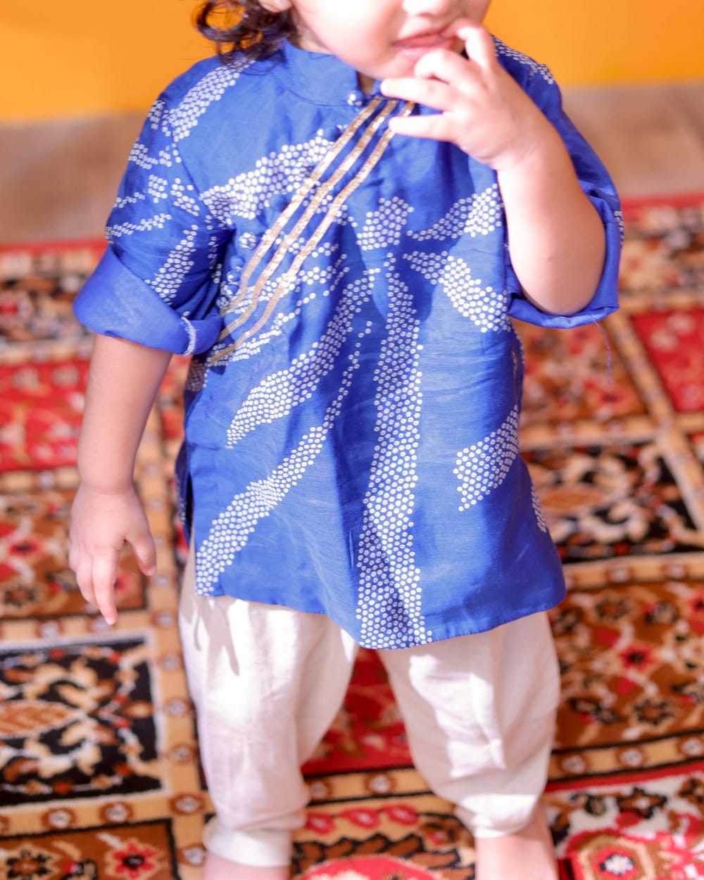 A boy in a blue bandhani kurta and cream pyjama