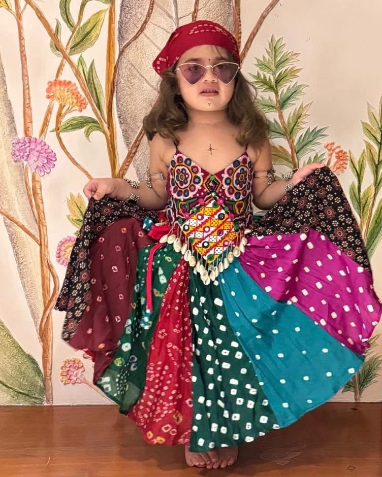 A girl holding the patchwork bandhani ghagra open, every panel a different cloth